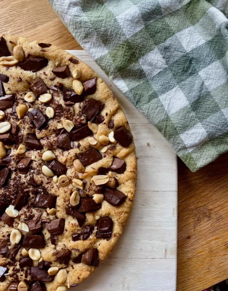 Cookie géant au chocolat et aux cacahuètes sur une planche en bois