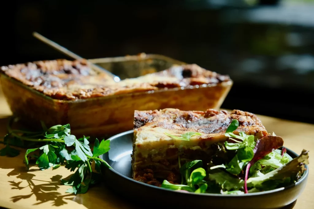 Part de lasagnes maison servie avec une salade verte